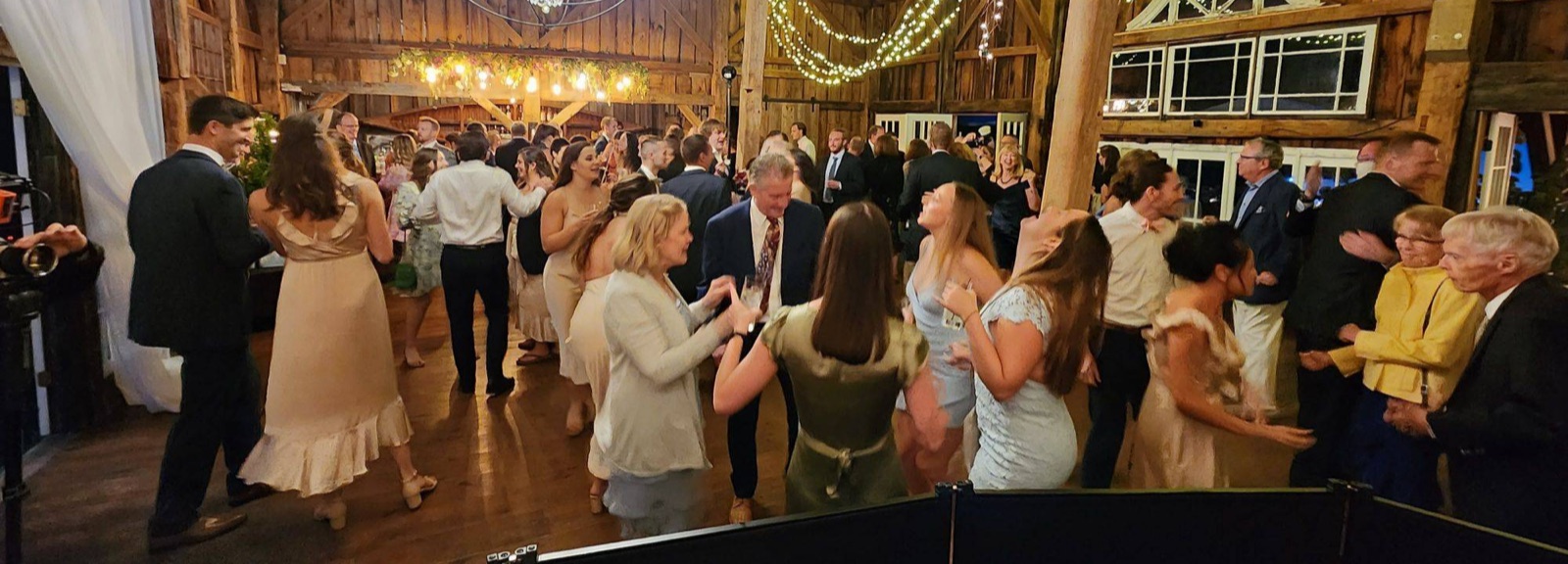 Guests dancing in a barn reception under string lights